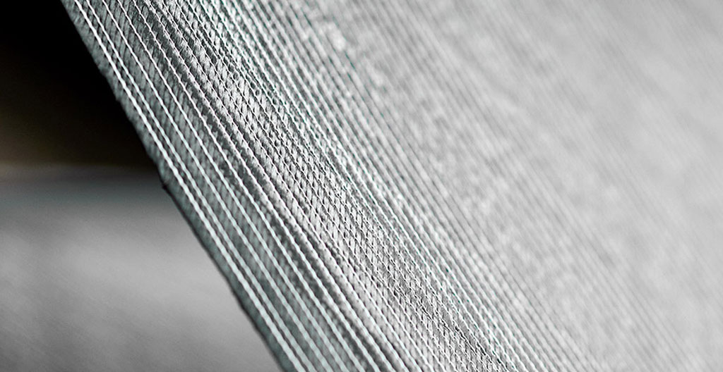 Gros plan sur un panneau de protection en composite fibres de carbone montrant la texture tissée caractéristique, manipulé par une main gantée d'ouvrier dans un atelier industriel de fabrication